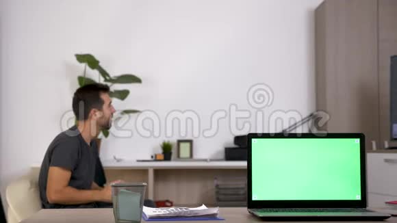 带有绿色模拟屏幕的电脑和一个在控制台上玩电子游戏的人在后台模糊视频的预览图