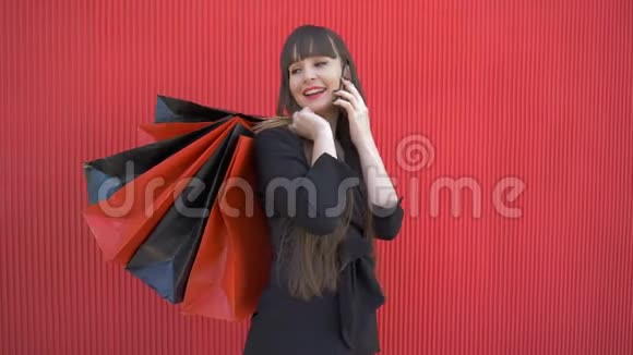 快乐的购物女孩用手机聊天手里拿着纸袋谈论成功的购物视频的预览图