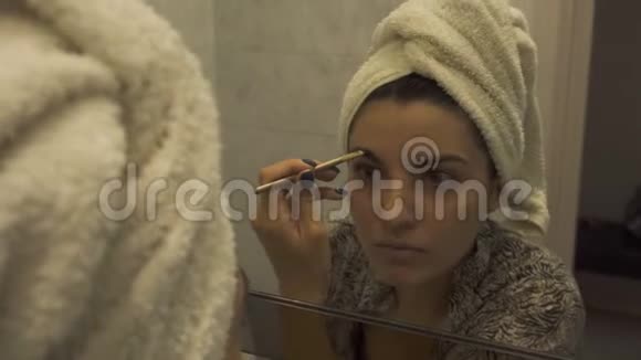 一个年轻漂亮的女人头上戴着毛巾洗澡后涂了化妆睫毛膏在一个视频的预览图