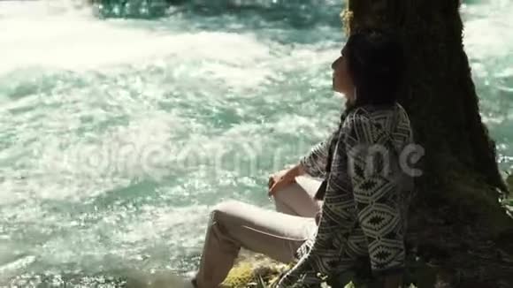 在公园散步的女人坐在河边看着水视频的预览图