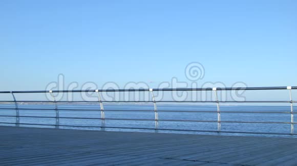 4美丽的女人走在码头上蓝色平静的大海在一边视频的预览图