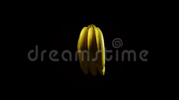 分离的成熟香蕉在水的喷雾下旋转在黑色的背景上视频的预览图