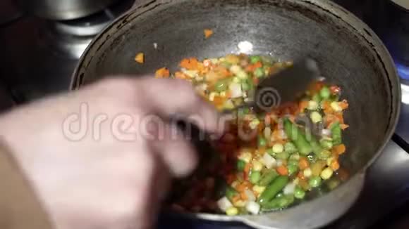 手把蔬菜混合物放入深锅中炸在家做健康的晚餐视频的预览图