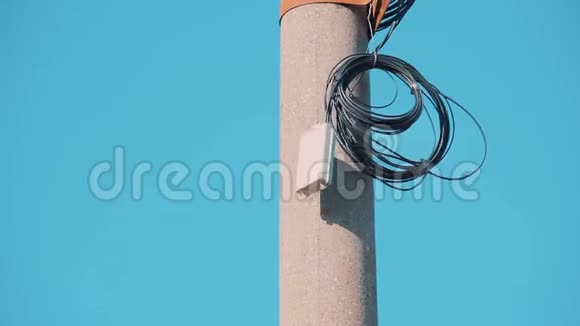 在高高的混凝土柱子上用环形的黑色电力电缆在蓝色的春天的天空上白色自动闭塞箱供晚上切换视频的预览图