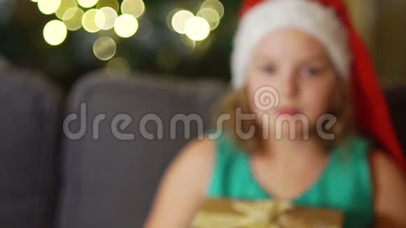 戴着圣诞帽的可爱女孩给了一个带丝带的金色盒子圣诞礼物亲密肖像除夕视频的预览图