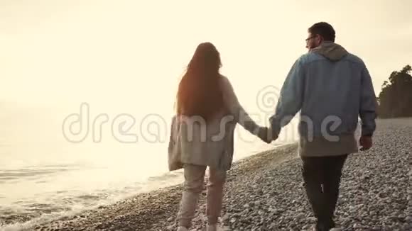 爱的一对情侣在日落时分在海边的卵石滩上散步视频的预览图