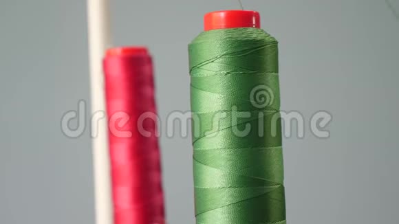 一条红绿棉线筒子在缝纫机主轴上的前景特写缝纫厂视频的预览图