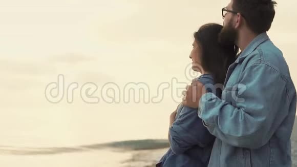 爱的男人和女人拥抱和观看日落时的潮汐波视频的预览图