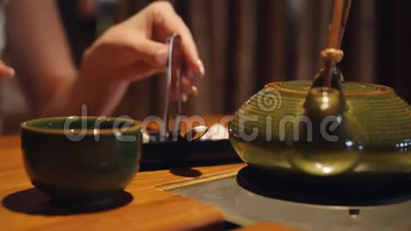 这位女士拿着特制的钳子糖块把它们放在餐厅的一杯茶里视频的预览图
