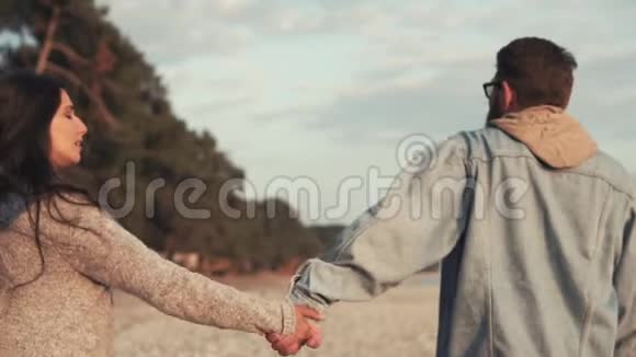 一对相爱的夫妻在海边散步他们牵着手视频的预览图