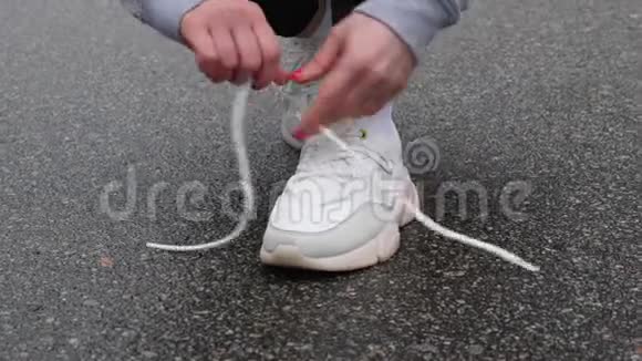 年轻迷人的白种人女孩在冬天在雪地公园跑步前系鞋带近距离射击视频的预览图
