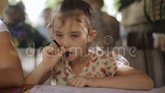 小女孩正在咖啡馆里画画一个小女孩用彩色铅笔画画坐在屋里视频的预览图