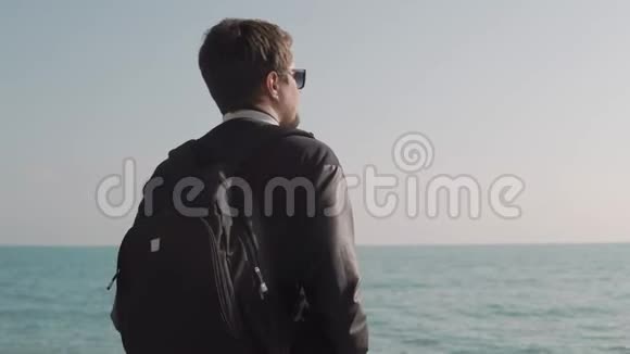 男人背着背包站在海边望着远处视频的预览图