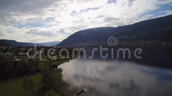 无人驾驶飞机观看奥地利湖Ossiacher海船和森林山镇Ossiach视频的预览图