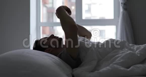 男人躺在床上拿着手机视频的预览图