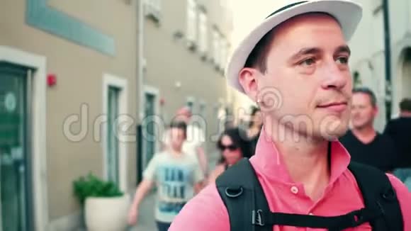 戴帽子的男旅行者沿着旅游街走视频的预览图