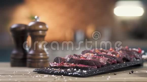 切片烤肉放在黑摊上厨师用手撒胡椒和盐特写慢动作视频的预览图