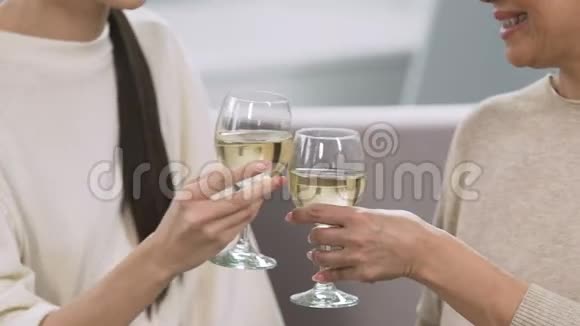 母亲和成年女儿抱着酒杯喝酒举行家庭庆典视频的预览图