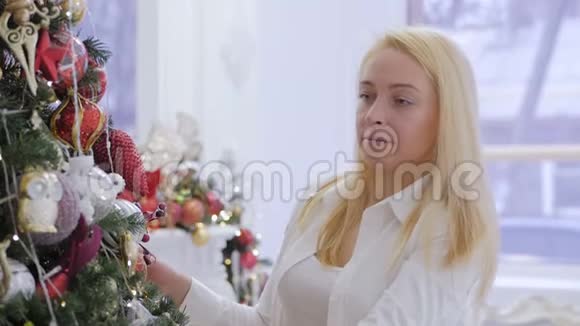 一个穿白色衬衫的漂亮女人装饰了一棵大圣诞树视频的预览图