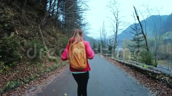 女徒步旅行者带着小背包在森林里的乡村道路上奔跑视频的预览图