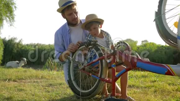 在农村父亲和他说话的时候一个顽皮的孩子在旋转自行车和脚踏车视频的预览图