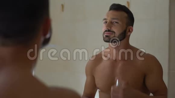 微笑的男人在浴室喷香水准备浪漫的约会视频的预览图