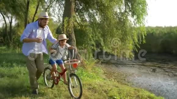 快乐的孩子学习骑自行车在他的父母的帮助下在农村的背景户外自然视频的预览图
