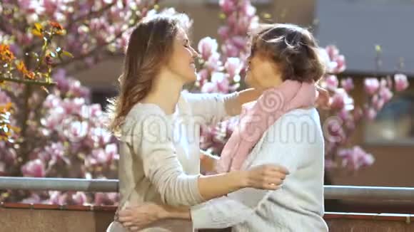 女儿抱着一位年迈的母亲背景是一朵盛开的玉兰花妈妈和女儿祝贺你们视频的预览图
