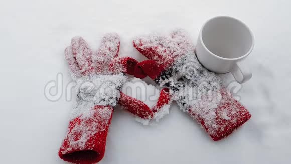 冬天的手套用一杯热咖啡在雪地上做成心脏的形状慢动作录像视频的预览图