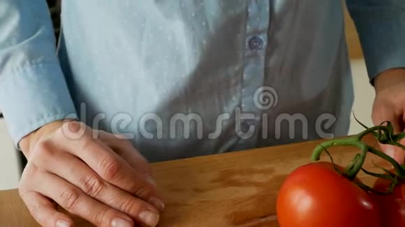 年轻女子用刀子切西红柿用来在木切割板上做沙拉视频的预览图