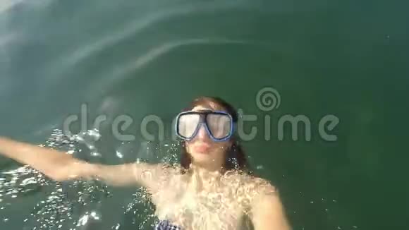 年轻的棕色头发女人的自拍在阳光明媚的日子里带着游泳面具躺在水里和水下没有资格享受POV视频的预览图