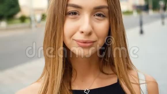 脸浅棕色头发的年轻女人看着相机的稳定镜头城市街道上的肖像美女视频的预览图