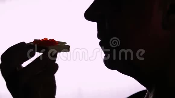 一个吃红鱼子酱三明治的人的头剪影概况视频的预览图