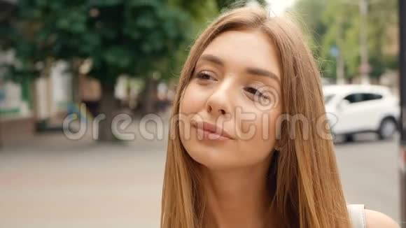 脸浅棕色头发的年轻女人看着相机的稳定镜头城市街道上的肖像美女视频的预览图