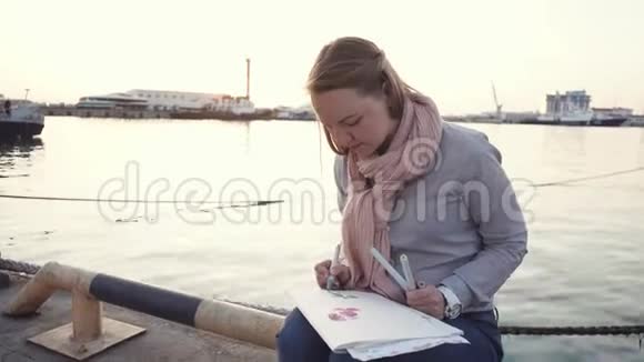 可爱的艺术家坐在河边视频的预览图