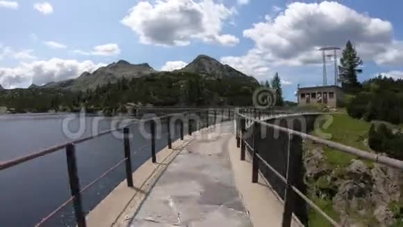 高山人工湖大坝上的高垂行走意大利阿尔卑斯山奥罗比意大利HikerPOV观点视频的预览图