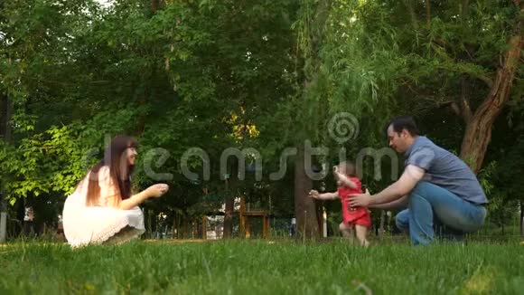 爸爸和妈妈被教导在公园里草地上散步小女儿家人在夏季公园休息视频的预览图