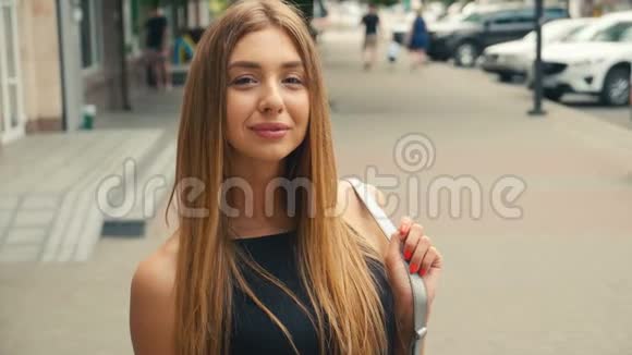 棕色头发的年轻女子的肖像看着相机的稳定镜头城市街道上的肖像美女视频的预览图