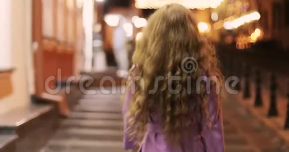 年轻的女人带着红色的卷发在夜城散步视频的预览图