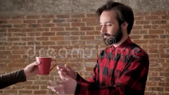 女孩手给留着胡子的帅哥一杯茶沟通观念砖背景视频的预览图