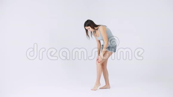 年轻女子膝关节疼痛关节疼痛白色背景孤立视频的预览图