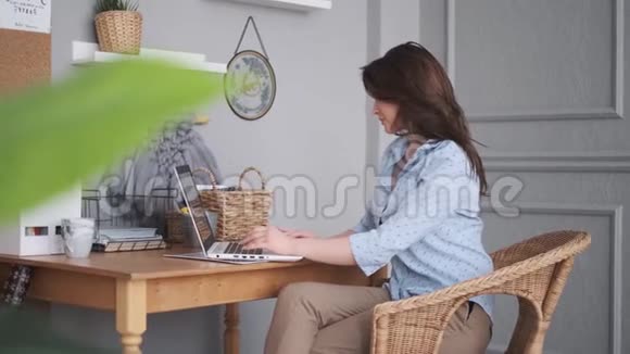 年轻女子在家里用笔记本电脑工作在舒适的工作场所的女孩视频的预览图