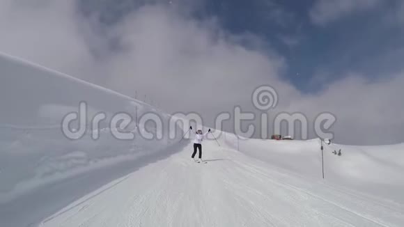运动滑雪者在冬季的山坡上滑雪并举起双手视频的预览图