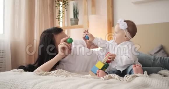 妈妈和小女儿在床上玩玩具积木视频的预览图