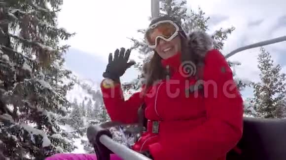 女子滑雪者爬上椅子抬到山顶挥舞着手视频的预览图