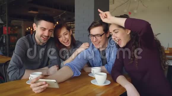 快乐的学生在咖啡馆里自拍做滑稽的脸和手势拥抱和笑视频的预览图