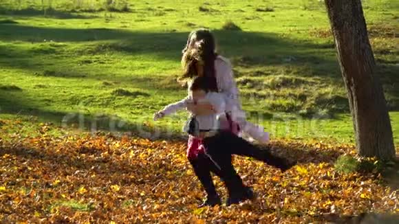妈妈和她的孩子们在秋天的森林里玩得很开心他们跳起来把树叶扔到空中他们笑着跌倒在地视频的预览图