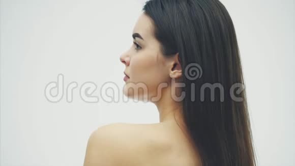 一个美丽的年轻女人完美的皮肤和自然的化妆在镜头前热带绿叶视频的预览图