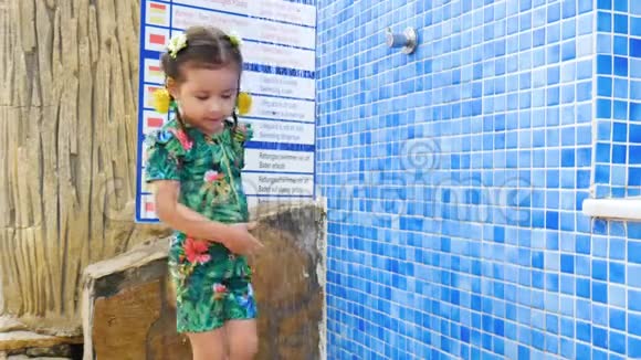 一个小女孩在淋浴下洗去沙子视频的预览图