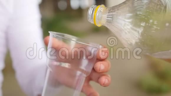把柠檬水从瓶子里倒入塑料玻璃里近距离射击视频的预览图